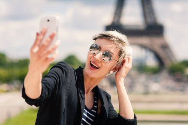 Mutlu genç kadın Paris'te cep telefonu ile selfie çekiyor, Fransa. Kişiye odaklanın.