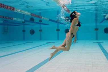 Yüzme havuzunda siyah bikini giyen kadın portresi.