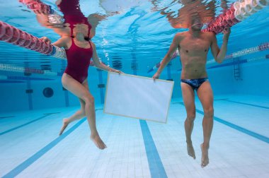 Couple holding plain blackboard inside swimming pool.