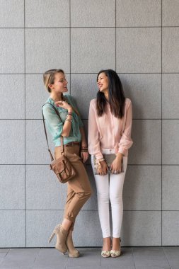 Genç kadınlar arka plan olarak modern duvar ile açık havada portre çizerler.. 