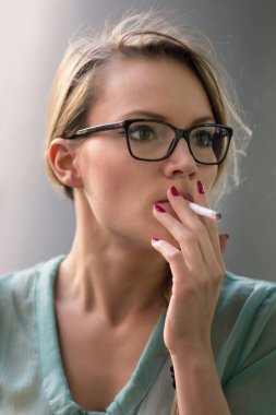 Genç Sarışın kadın açık havada sigara içen. Sığ alan derinliği. 