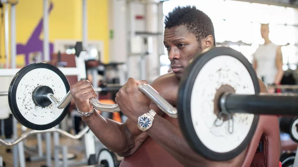 Joven retrato de hombre negro haciendo ejercicio con pesas en el gimnasio . — Foto de Stock