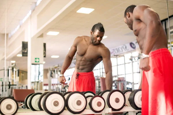 Hombre negro fuerte haciendo ejercicio con pesas en el gimnasio . — Foto de Stock