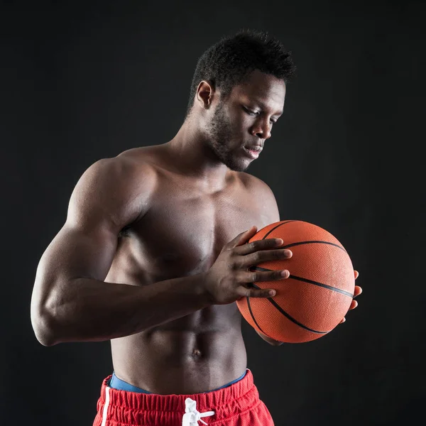 Fiducioso giovane uomo nero a torso nudo con pallone da basket contro bla — Foto Stock