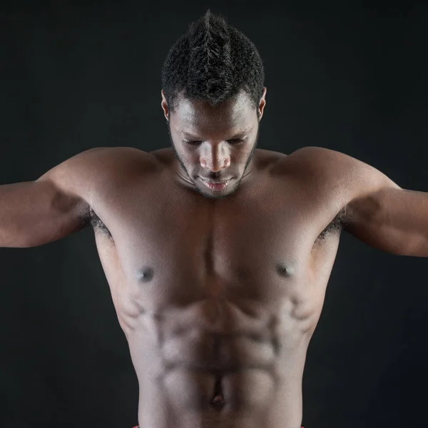 Sterke jonge man shirtloze portret tegen zwarte achtergrond. — Stockfoto