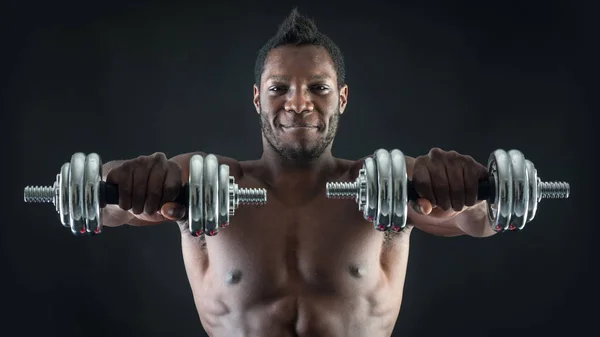 Smiling young man shirtless portrait training with dumb-bells ag — Stock Photo, Image