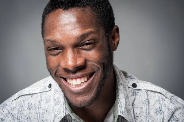 Lachen zwarte man close-up portret tegen grijze achtergrond. — Stockfoto