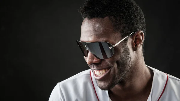 Laughing black man close up portrait with sunglasses against dar — Stock Photo, Image