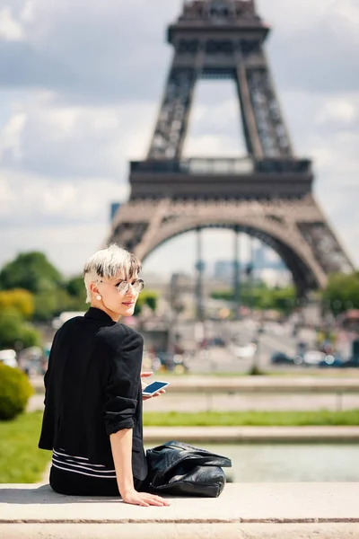 エッフェル塔の前に携帯電話で美しい若いブロンドの女性の肖像画 フランス フィルタリングされた画像 — ストック写真