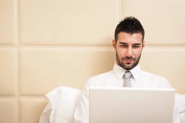 Jonge zakenman werkt met computer in hotelkamer. — Stockfoto