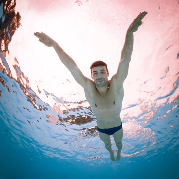 Onderwater man binnen zwembad van onderen. — Stockfoto