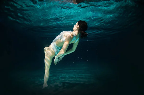 Underwater woman portrait in swimming pool at night. Dreamlike i — Stock Photo, Image