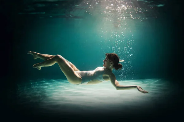 Underwater woman portrait in swimming pool at night. Dreamlike i — Stock Photo, Image