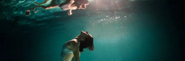 Undervannskvinne panoramatportrett i svømmebasseng om natten. D – stockfoto