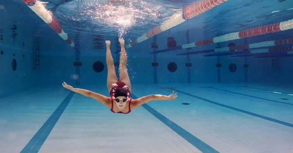 Női profi úszó piros fürdőruhát visel úszás közben — Stock Fotó