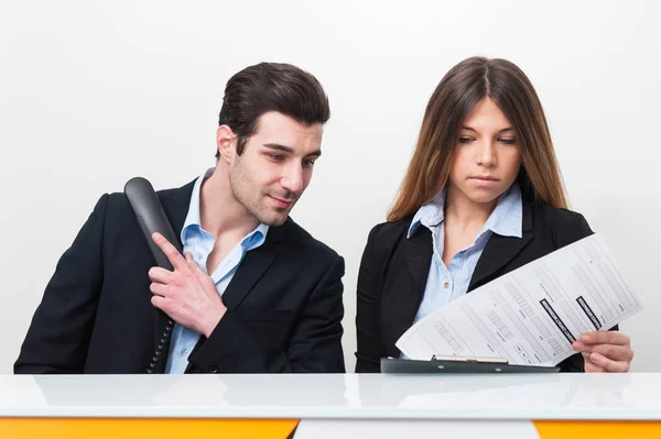 Joven hombre y mujer en el trabajo como recepcionista en el hospital hablando —  Fotos de Stock