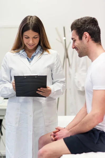 Medico visita il suo paziente maschile e prendere appunti in ufficio . — Foto Stock