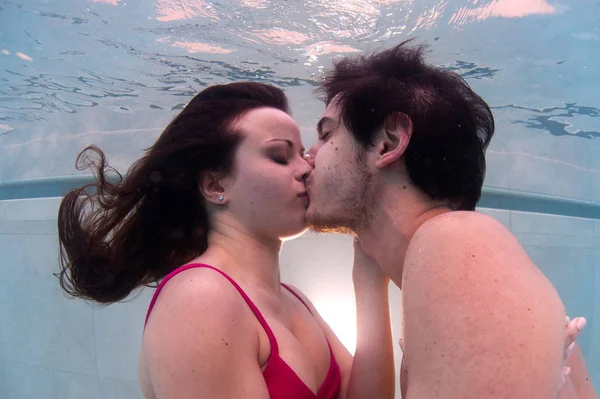 Underwater romantic couple kissing in swimming pool.