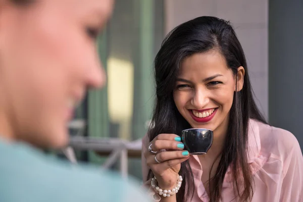 Young brunette woman drinking coffee with friend in a cafe outdo — Stock Photo, Image