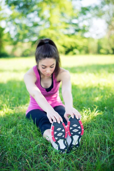 公園で彼女の足を屋外に伸ばす若い女性の肖像画 — ストック写真