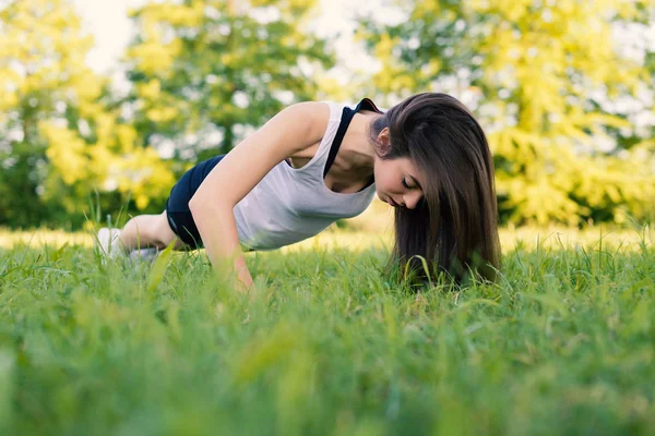年轻女子肖像练习在公园户外练习俯卧撑运动 — 图库照片
