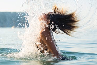 Etkin genç sarışın kadın plajda su sıçraması. 