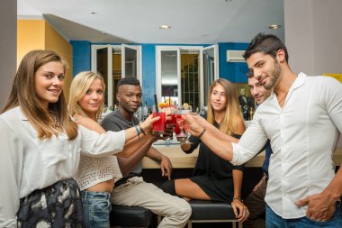 Young friends having fun in a bar drinking cocktail. 