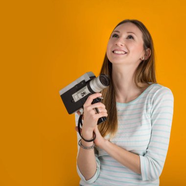 Turuncu arka plan karşı vintage film kamera yakın gülen kadın. 