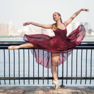 New Jersey rıhtımında dans eden genç ve güzel bir balerin. Arka planda New York silueti var. Balerin Projesi.