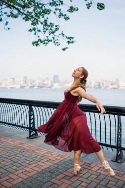 New Jersey rıhtımında dans eden genç ve güzel bir balerin. Arka planda New York silueti var. Balerin Projesi.