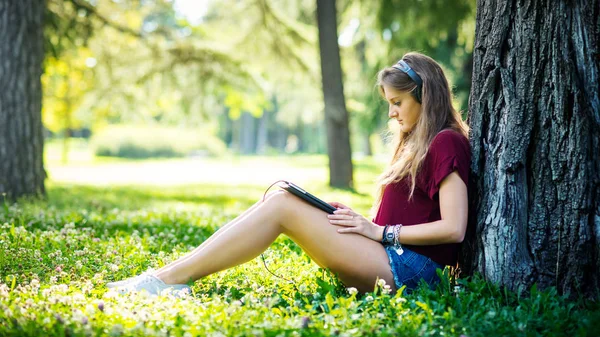 公園で屋外で音楽を聴いている若い女性の肖像 — ストック写真