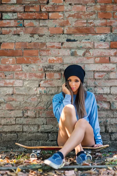 Adolescente íntimo retrato sentarse en monopatín contra la pared de ladrillo . — Foto de Stock