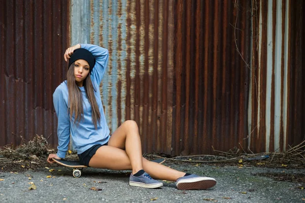 Full body teenager portrait with skateboard against old grunge r