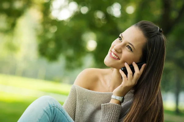 公園で屋外で電話で話す幸せな若い女性 — ストック写真