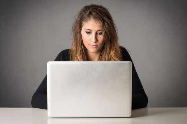 Woman working on a laptop against grey grunge background.