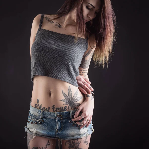 Primer plano de la hermosa mujer con tatuaje usando pantalones vaqueros dolor corto — Foto de Stock