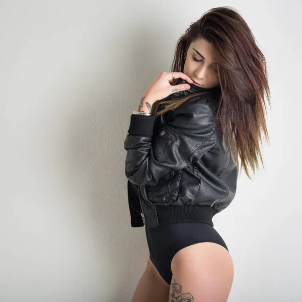 Sensual woman with tattoo wearing leather jacket against white w — Stock Photo, Image