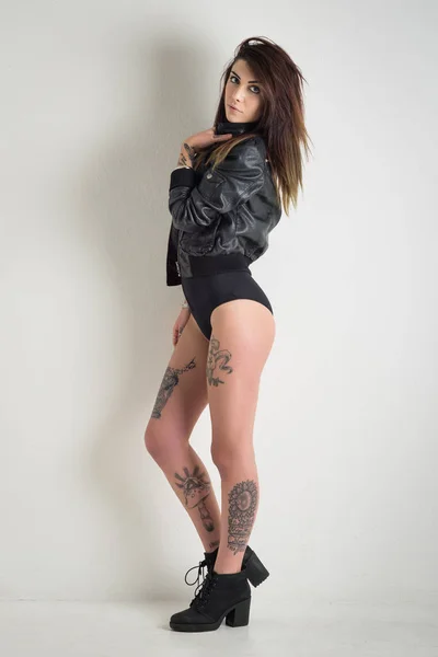 Sensual woman with tattoo wearing leather jacket against white w — Stock Photo, Image