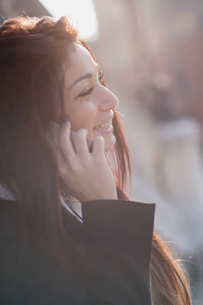 休闲的年轻女子肖像在公园的电话交谈 具有背光效果的滤镜图像 — 图库照片