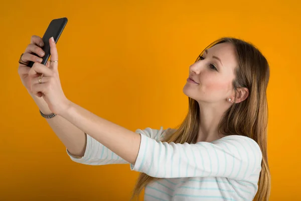 Genç Bir Kadın Portakal Rengi Arka Planda Cep Telefonuyla Selfie — Stok fotoğraf