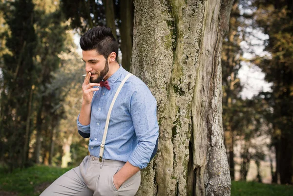 Smiling Hipster Young Man Relaxing Smoking Cigarette Outdoors Park — Stock Photo, Image