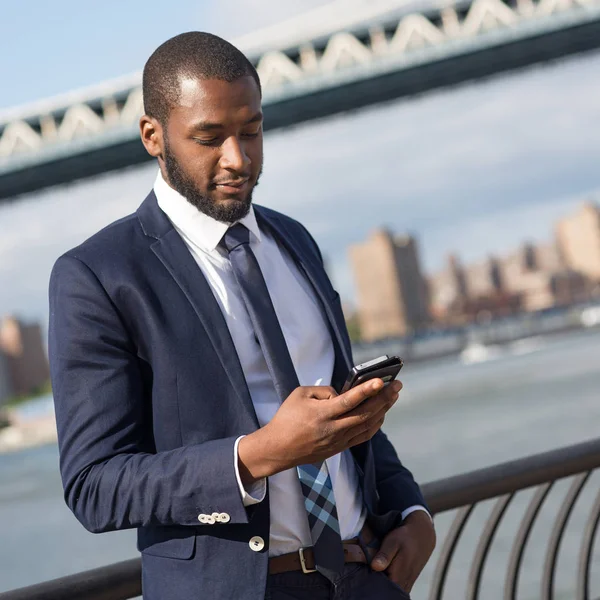 Молодий бізнесмен користується мобільним телефоном з Мангеттенським мостом. — стокове фото