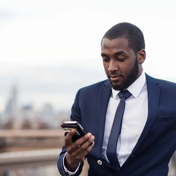 Νεαρός επιχειρηματίας χρησιμοποιεί κινητό τηλέφωνο στη γέφυρα του Μπρούκλιν. Νέα Υόρκη. — Φωτογραφία Αρχείου