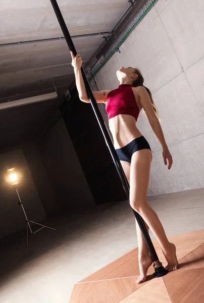 美しい女性がポールダンスをする 産業用コンクリートの背景で撮影 — ストック写真
