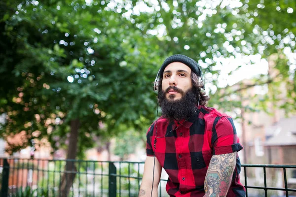 Young tattooed man portrait relaxing in a park in Shoreditch borough. London, UK. Hipster style.