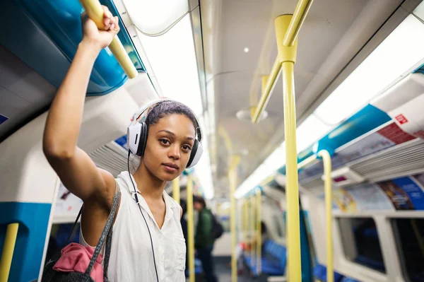 Young woman portrait inside underground in London listening to m — Stock Photo, Image