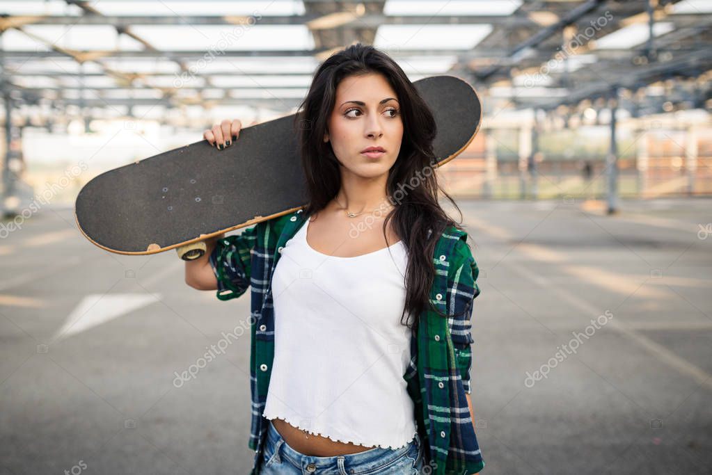 Teenager with skateboard portrait outdoors in a parking area. 