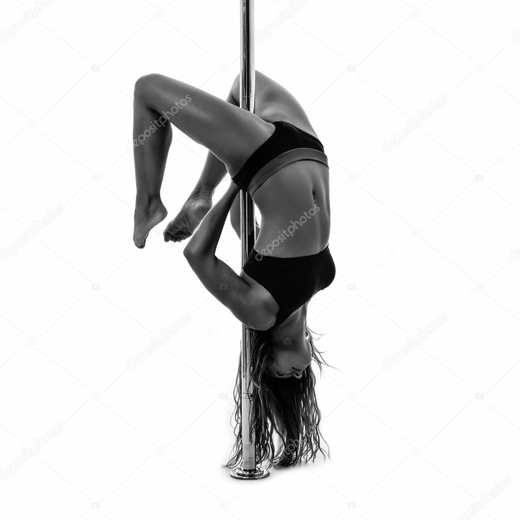 Silouette of woman performing pole dance. Studio shot, black and white image.