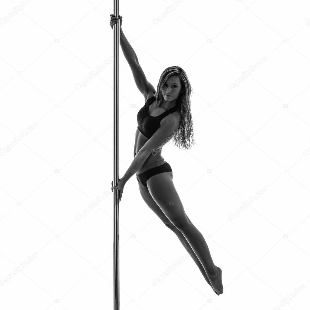 Silouette of woman performing pole dance. Studio shot, black and white image