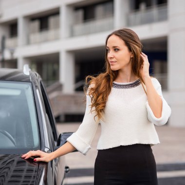 Woman portrait close to her car in the city. Filtered image.